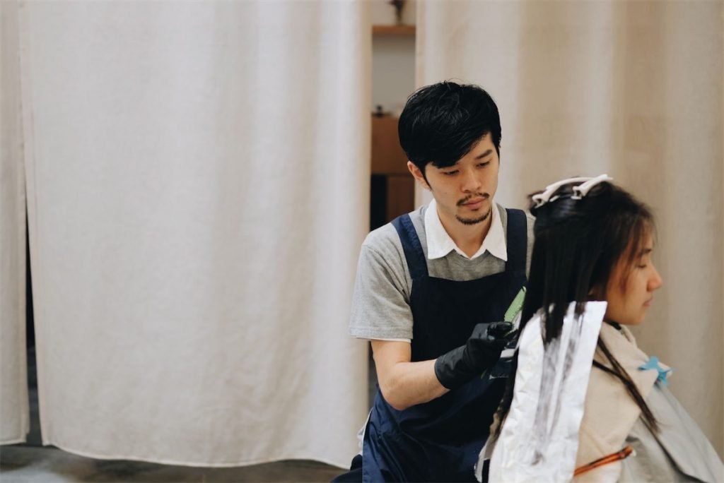 A male Japanese stylist dyeing the hair of a woman in a hair salon in Singapore