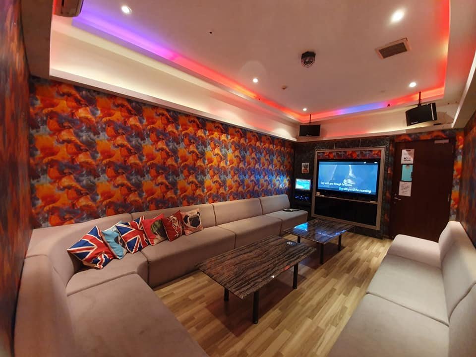 Ten dollar ktv club room with beige sofa, a brown table, colorful lights and tv
