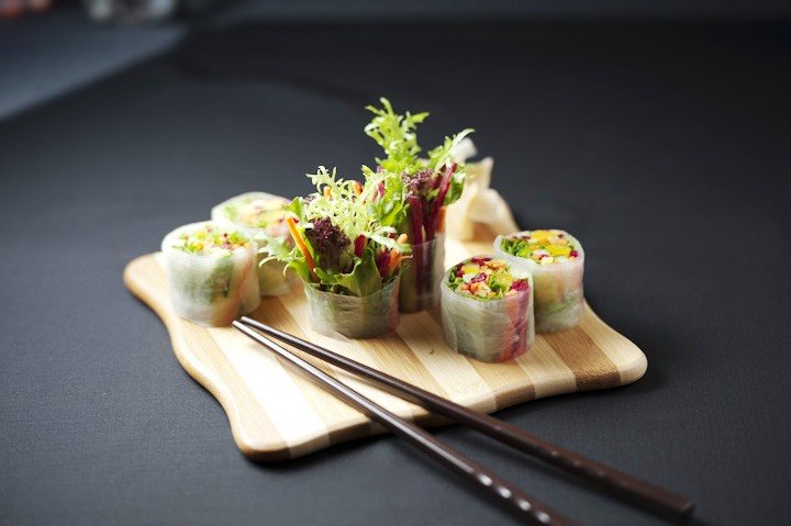 vegetable wraps on a wooden board and a pair of chopsticks