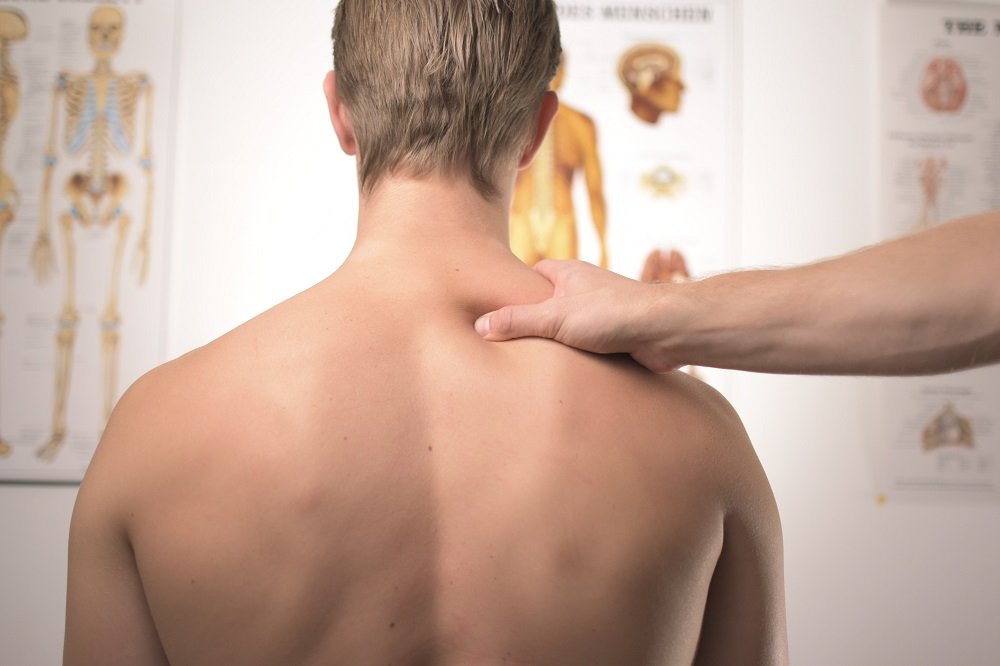 chiropractor pressing the upper back part of a man