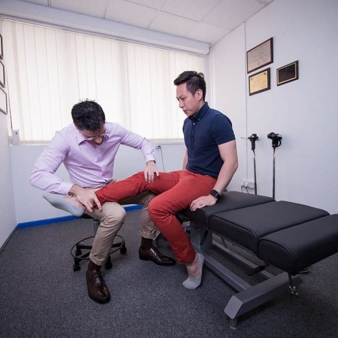 chiropractor checking up on his clients legs in his clinic in singapore