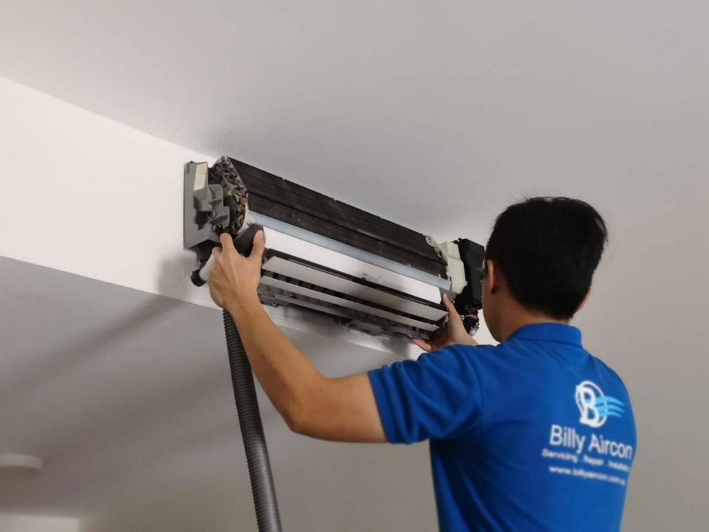 A technician from Billy Aircon servicing an aircon unit